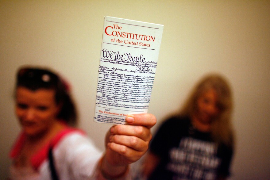 WASHINGTON - JULY 25:  Elementary school teacher Lisa Petry of Virginia Beach, Virginia, holds up a copy of the U.S. Constitution while waiting in line to attend  the House Judiciary Committee's hearing on the "Executive Power and Its Constitutional Limitations" at the Rayburn House Office Building on Captiol Hill July 25, 2008 in Washington, DC. Spearheaded by former Democratic presidential hopeful Rep. Dennis Kucinich (D-OH), the hearing included authors, former politicians, university professors and other opponents of the Bush Administration.  (Photo by Chip Somodevilla/Getty Images)