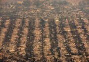 An aerial view of rows of streets filled with gray rubble where homes once stood.