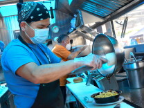  Justin Tulus (left) prepares food for customers as Tom Tulus (right) takes customer's order at their truck StopBye Cafe