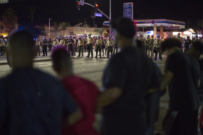 EL CAJON, CA - SEPTEMBER 29: Protesters lock arms as officers amass after an unlawful assembly is declared near the site where an unarmed black man, Alfred Olango, 38, had been shot by police earlier this week on September 29, 2016 in El Cajon, California. A family member called police to help Olango as he was undergoing an emotional breakdown but shot him when he quickly pulled out an electronic cigarette device. He died later that evening.   (Photo by David McNew/Getty Images)