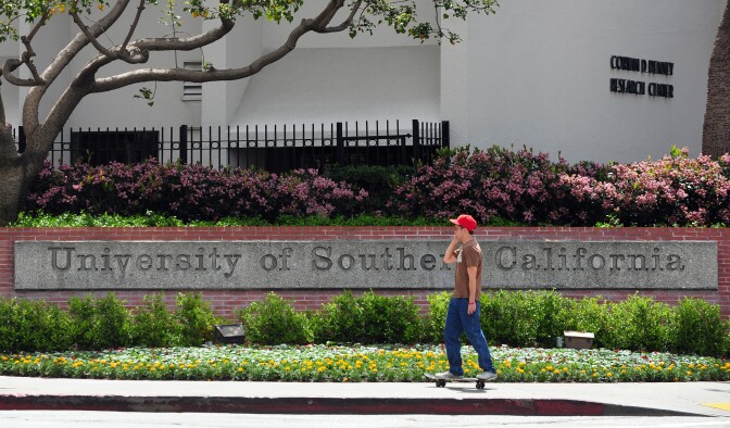 A student rides his skateboard past an entrance to the University of Southern California (USC) campus in Los Angeles on April 11, 2012.