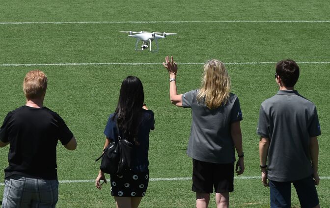 One person waves to the camera on a drone as people pose for a photo, July 3, 2016, at the Rose Bowl stadium in Pasadena, California.
NASA's solar-powered Juno spacecraft is scheduled to enter into orbit around Jupiter on July 4 to begin an in-depth study of the planet's formation, evolution and structure. The key event on July 4 is a 35-minute engine burn at 11:18 p.m. EDT (0318 GMT on Tuesday), which is designed to slow Juno down enough to be captured by Jupiter's powerful gravity. / AFP / Robyn Beck        (Photo credit should read ROBYN BECK/AFP/Getty Images)