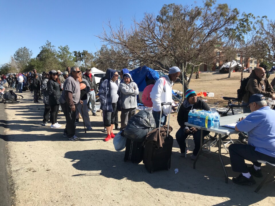 A line of homeless people at the Santa Ana riverbed wait to get connected with a motel room or shelter. on Tuesday, Feb. 20, 2018.