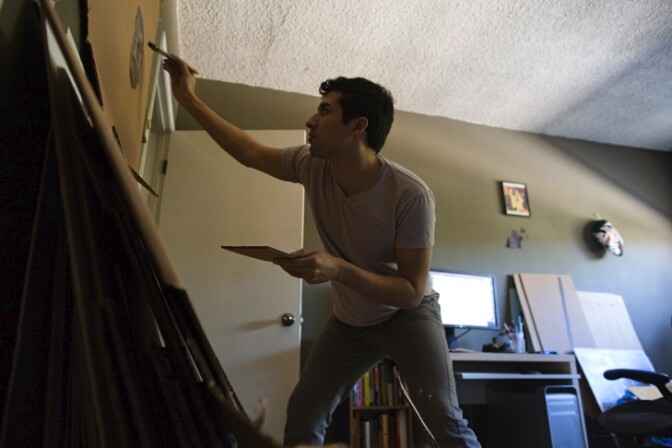 Ramiro Gomez paints in a spare bedroom that he uses as a studio in his West Hollywood apartment.