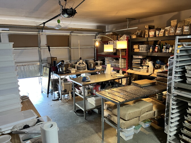 A kitchen inside a garage with trays and tables and flour mixers.