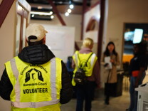 Two people wearing reflective vests walk through a hallway.