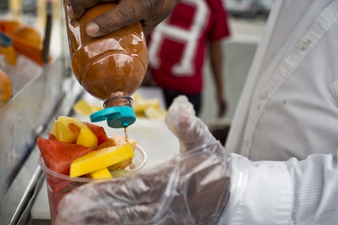 Delfina Flores puts chili powder and lime juice on fruit for a customer on Tuesday, Nov. 11, 2014 on Figueroa Street in Highland Park.