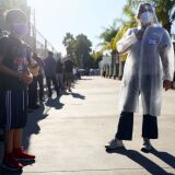 SAN FERNANDO, CALIFORNIA - DECEMBER 2: A USC research team member (R) recruits families to participate in a rapid antigen testing program as people wait in line at a walk-up COVID-19 testing site on December 2, 2020 in San Fernando, California. California reported 20,759 new coronavirus cases today, a one-day record for the state, amid a new limited stay-at-home order in Los Angeles County. (Photo by Mario Tama/Getty Images)
