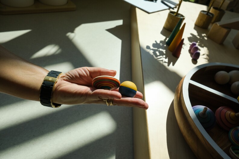 An outstretched hand holds a pair of colorful wooden tops.