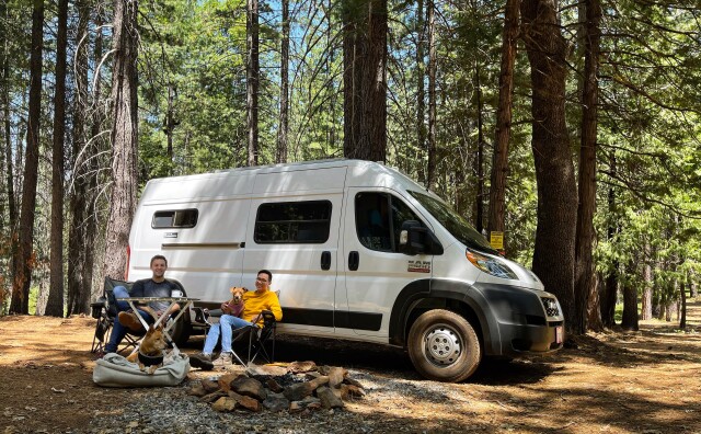 Patrick and Arthur at a campsite with their van and two dogs.