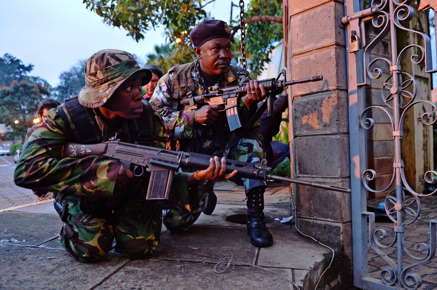 Kenyan soldiers take cover after heavy gunfire near Westgate mall in Nairobi on September 23, 2013. Kenyan Defence troops remain inside the mall, in a standoff with Somali militants after they laid siege to the shopping centre shooting and throwing grenades as they entered. Somali Shebab militants on September 23 threatened to kill hostages they are holding in the Nairobi shopping mall as Kenyan troops move to end their siege.