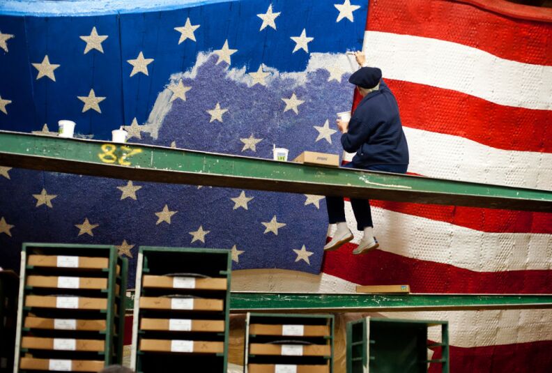 Shari Kennedy of Kiwanis International adds color to an American flag on a float in the Rosemont Pavilion on Thursday, days before the Rose Parade on New Year's Day. The float uses wheat, corn kernels, green tea leaves, parsley, and crushed split peas, among other materials, for its color.