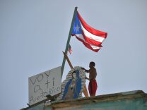 Javier places on his house next to a flag of Puerto Rico, a placard that read in spanish "Voy a ti Puerto Rico" (I come to you Puerto Rico), in Yabucoa, in the east of Puerto Rico, on September 28, 2017.
The US island territory, working without electricity, is struggling to dig out and clean up from its disastrous brush with hurricane Maria, blamed for at least 33 deaths across the Caribbean. / AFP PHOTO / HECTOR RETAMAL        (Photo credit should read HECTOR RETAMAL/AFP/Getty Images)