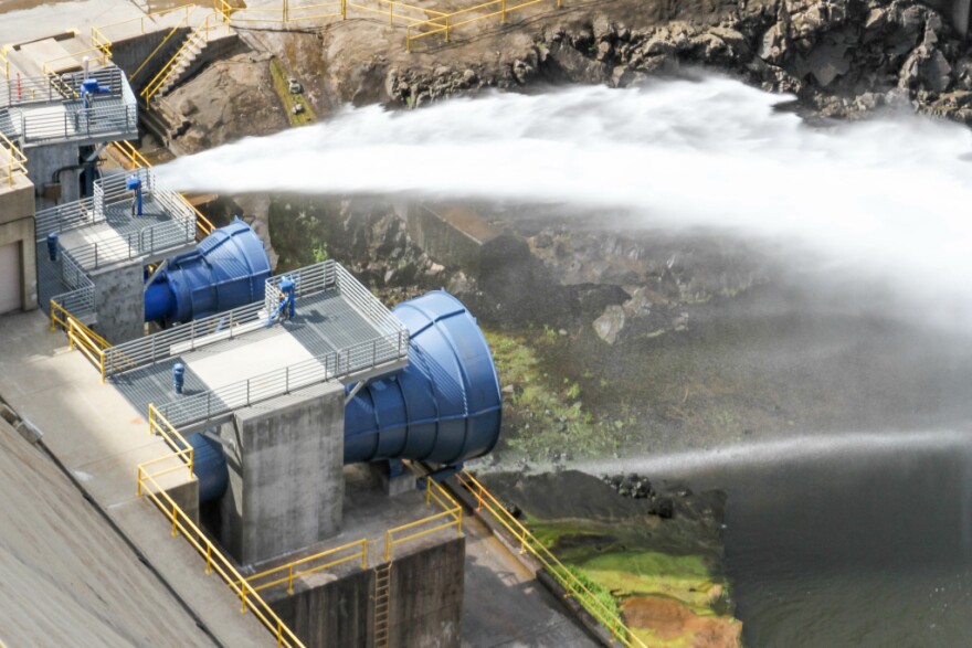 Here Is Where Our Water Comes From - Water sprays from a dam outlet across the air and onto a river.