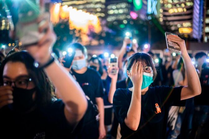 TOPSHOT - Secondary school students cover their right eye as they hold up their phone torches while attending a rally at Edinburgh Place in Hong Kong on August 22, 2019. - Hong Kong student leaders on Thursday announced a two-week boycott of lectures from the upcoming start of term, as they seek to keep protesters on the streets and pressure on the government. (Photo by Anthony WALLACE / AFP)        (Photo credit should read ANTHONY WALLACE/AFP/Getty Images)