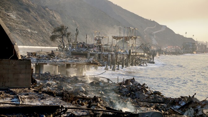 Smoldering ruins on pillars that are set into the ocean.