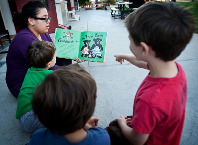 Children's Center teacher Karina Diaz reads a book to preschoolers on Tuesday afternoon in the center's large outdoor space.