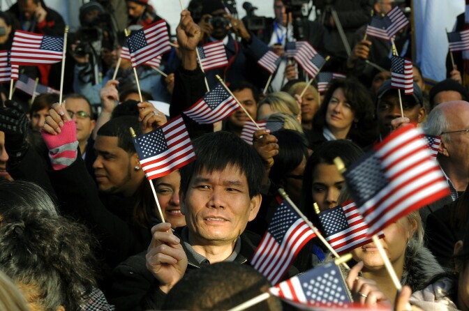 New citizens wave US flags before being sworn in during a Naturalization Ceremony.
