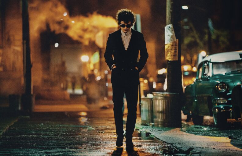 Timothée Chalamet walks down a street at night, in character as Bob Dylan in the 2024 film "A Complete Unknown."