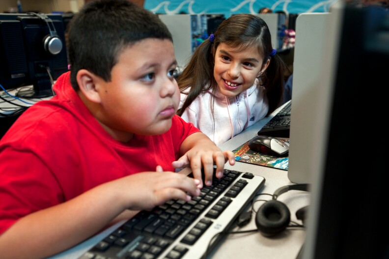 Third grader Natalia Garcia, left, helps her classmate, Efren Gonzalez, during a computer lab class on Wednesday morning.