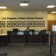 A security guard sits at a desk under a wall that says "Los Angeles Unified School District."