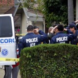 Immigration and Customs Enforcement agents lining the driveway of a home in Carson salute as the body of an ICE agent Myron Chisem, who was covered by an American flag as his body was wheeled to a coroner's van on Thursday. His14-year-old son was arrested Thursday morning on suspicion of murder.