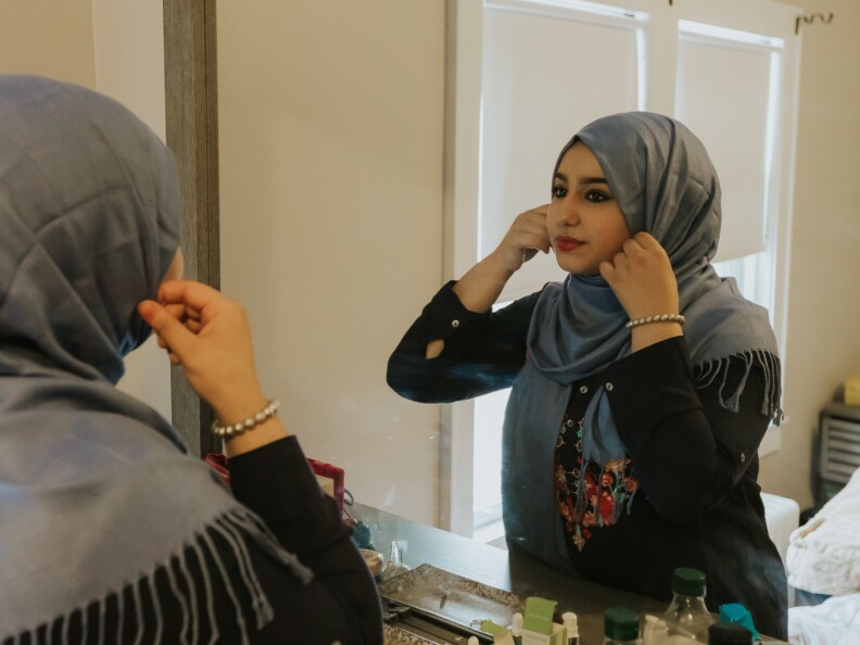 Ammal, 18, adjusting her hijab in the mirror.
