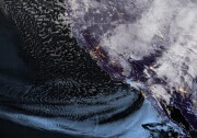 A satellite view of the earth shows clouds moving south along the west coast of the U.S.
