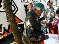 Former Army Sgt. Dennis Anderson, a homeless veteran, signs up as he  gets a slice of pizza that was handed out from the Little Caesars Love Kitchen, a mobile pizza kitchen, in front of the Department of Veterans Affairs building September 17, 2007 in Washington, DC. The Love Kitchen was in town to provide hot pizza meals to homeless people including homeless veterans. Little Caesar's founder Michael Ilitch was awarded with the Secretary's Award Monday by the Department of Veterans Affairs to recognize his support of veterans.