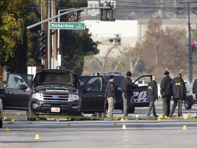 Investigators gather around a Black SUV that was involved in Wednesday's police shootout with suspects, Thursday, Dec. 3, 2015, in San Bernardino, Calif.  A heavily armed man and woman dressed for battle opened fire on a holiday banquet for his co-workers Wednesday, killing multiple people and seriously wounding others in a precision assault, authorities said. Hours later, they died in a shootout with police. (AP Photo/Jae C. Hong)