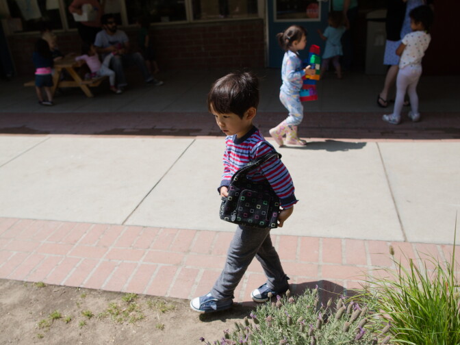 A preschool student walks with a women's handbag at the Child Educational Center in La Cañada, which is trying to counter learned gender schemas