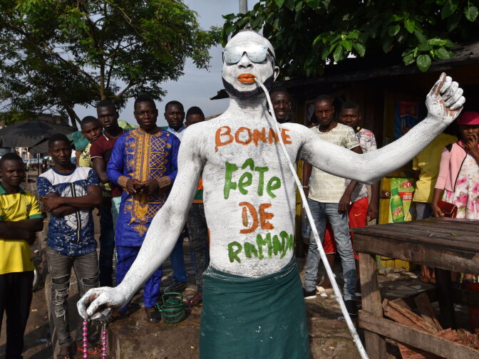 TOPSHOT - A man wearing makeup reading "Happy Ramadan" parades through the streets of Abidjan on June 25, 2017, as Muslims celebrate the Eid al-Fitr holiday.
Muslims worldwide celebrate the Eid al-Fitr holidays, which mark the end of the holy fasting month of Ramadan.  / AFP PHOTO / Sia KAMBOU        (Photo credit should read SIA KAMBOU/AFP/Getty Images)