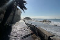 A flooded boardwalk along a coastline with eroded sand berms.