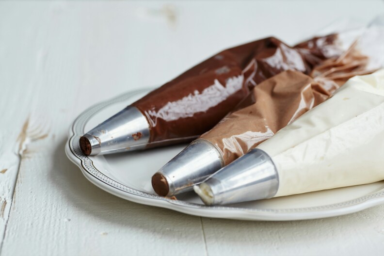 Three piping bags on a plate, with different kinds of chocolate inside — dark, milk, and white.