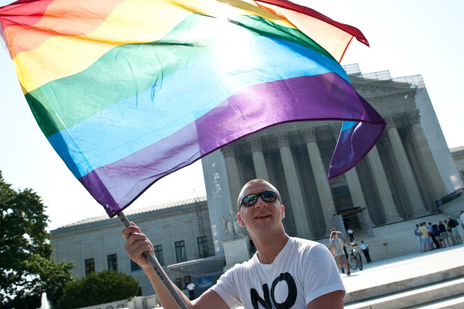 A gay rights activist waves a rainbow flag in front of the U.S. Supreme Court in June, a day before the ruling on the Defense of Marriage Act.