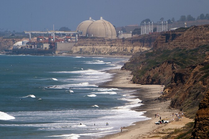 A beach with ocean on the left, bluffs on the right, and a nuclear reactor in the background.
