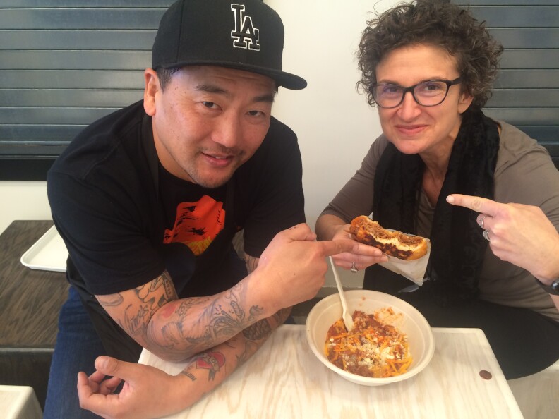 Roy Choi (L) and host Alex Cohen with some of the new foods on the menu at LocoL, Choi's new fast food restaurant opening in the Watts neighborhood on January 18, 2016.