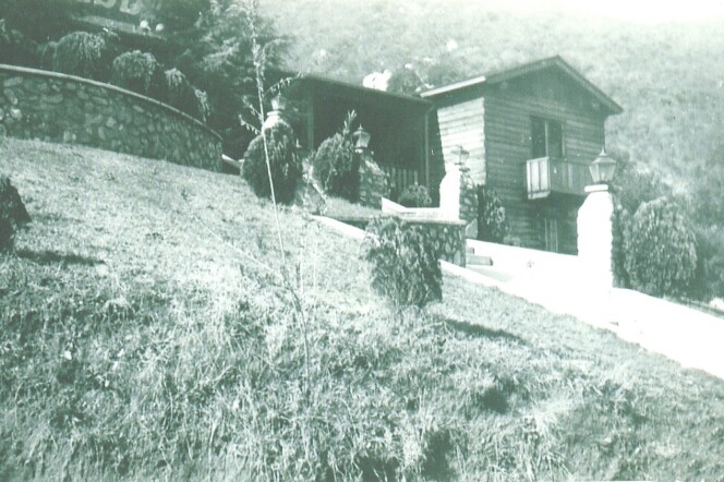 A brick and wood structure is seen in black and white. The Verdugo Lodge is at the top of a hill. 