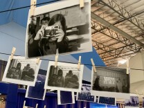 Dozens of photos are strung on clotheslines and attached by clothespins. 