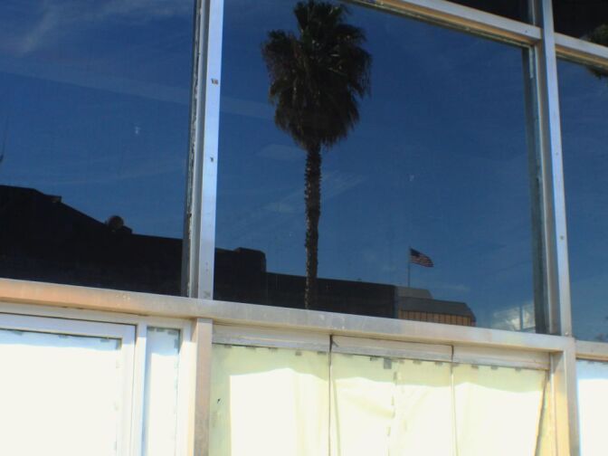 San Bernardino City Hall can be seen in the reflection of this window of a vacant downtown storefront.