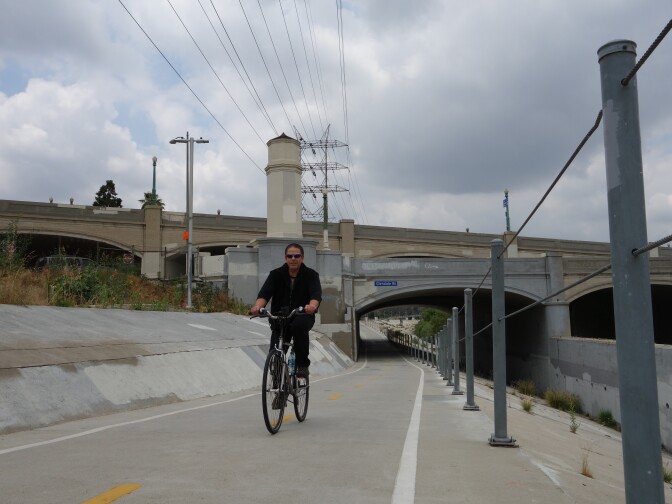 A cyclist bikes alongside the Los Angeles River near the Glendale-Hyperion complex of bridges, which are the subject of reconstruction plans.