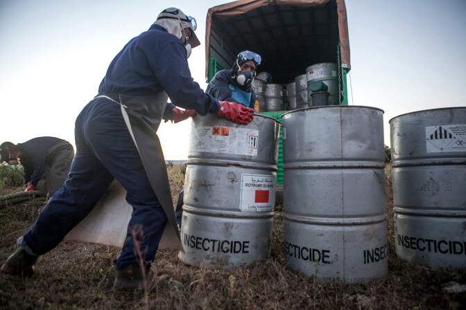 Members prepare insecticide for a helicopter equipped for pesticide spreading.