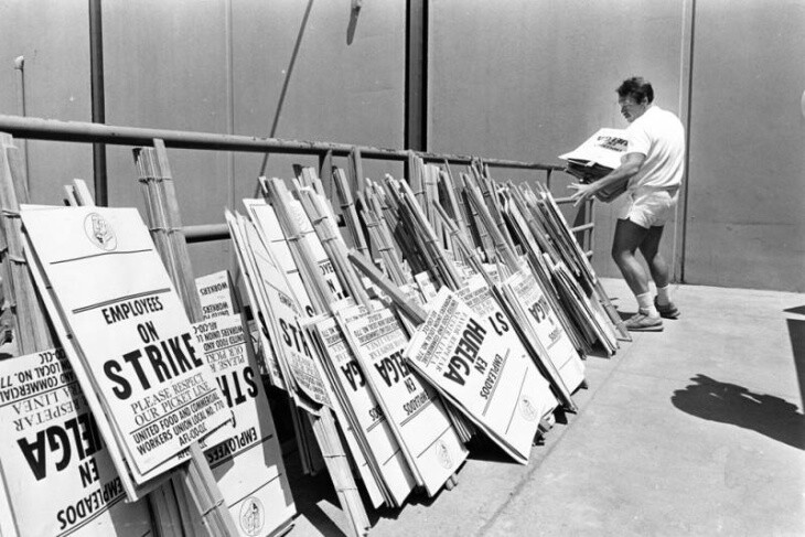 A pile of black and white signs against a railing read: "Employees on Strike" with some in Spanish.