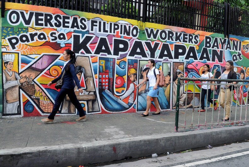 People walk past a mural honoring overseas Filipino workers in Manila on July 7, 2014. The government estimates there are ten million overseas Filipino workers, or about a 10th of the population, whose dollar remittances account for about 10 percent of gross domestic product.