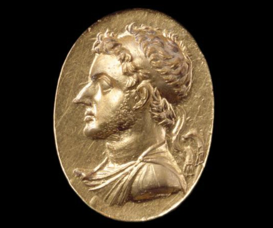 A portrait in gold of a Ptolemy on a ring. The disc is 3/4" high, and was made by an unknown Egyptian artist c.186–145 BC