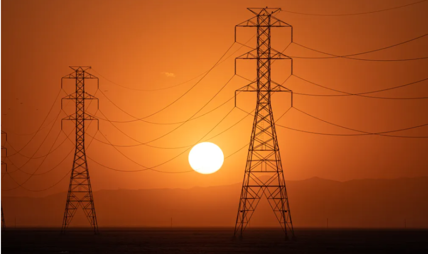 A sun sets near an electric tower.