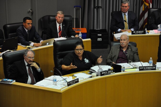 FILE - Los Angeles Unified School Board member Mónica García (center) speaks during a meeting, as colleagues George McKenna (left), Scott Schmerelson (right) and district staff (rear) listen.