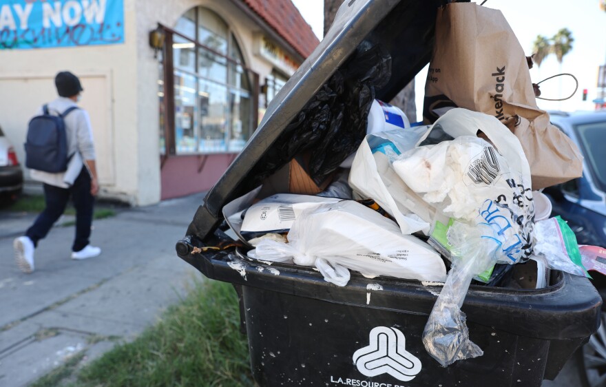 Discarded plastic and other material overflow in a garbage bin.