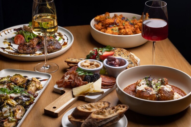 An assortment of dishes from Evil Twin, including charcuterie and wine glasses.