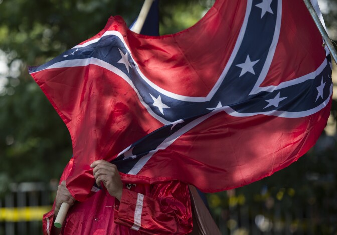 A member of the Ku Klux Klan holds a Confederate flag over his face during a rally, calling for the protection of Southern Confederate monuments, in Charlottesville, Virginia on July 8, 2017.
The afternoon rally in this quiet university town has been authorized by officials in Virginia and stirred heated debate in America, where critics say the far right has been energized by Donald Trump's election to the presidency.
 / AFP PHOTO / ANDREW CABALLERO-REYNOLDS        (Photo credit should read ANDREW CABALLERO-REYNOLDS/AFP/Getty Images)